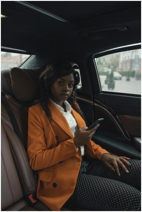 A professional woman in a luxury car, using her sm