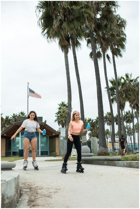 Two women enjoy rollerblading in a palm-lined park