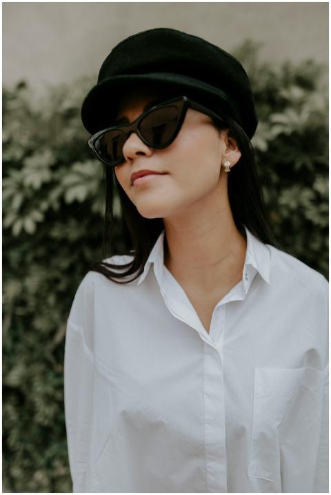 A fashionable woman in a white shirt and hat with