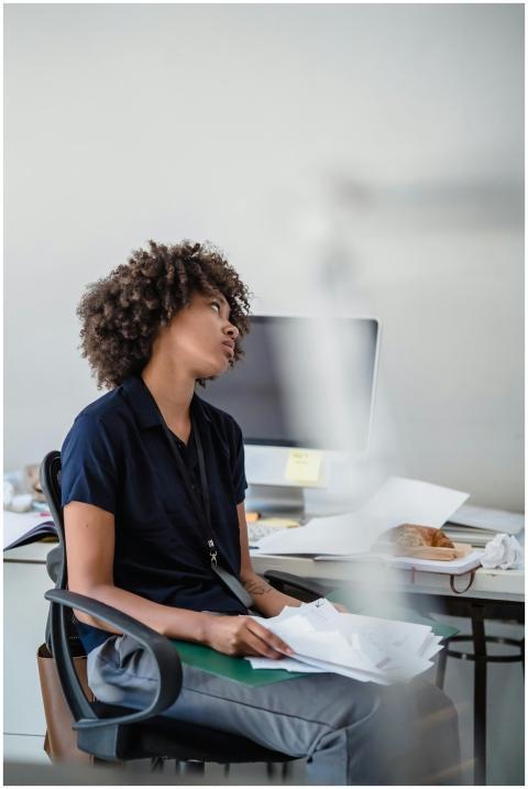 Woman experiencing stress at her office desk surro