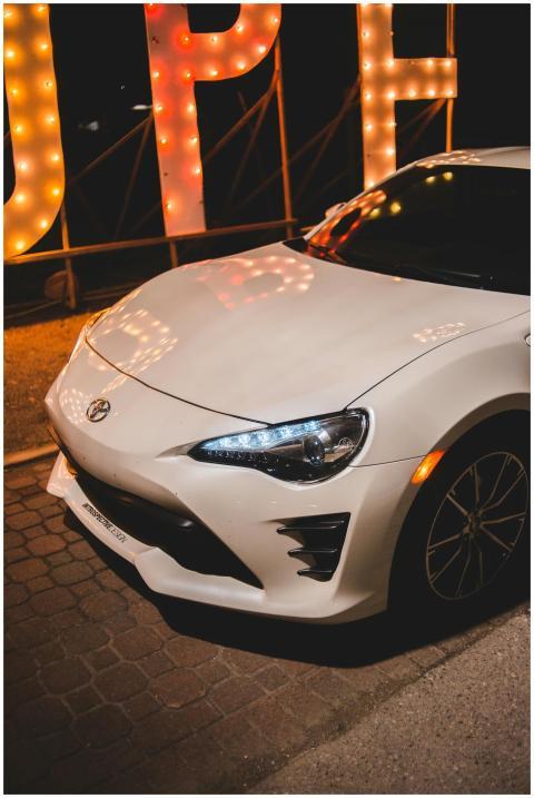 Front view of a white sport car parked at night wi