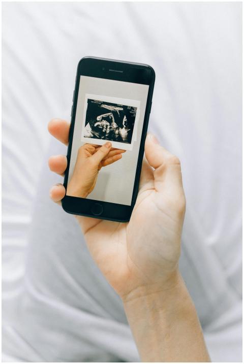 A hand holding a smartphone displaying a pregnancy