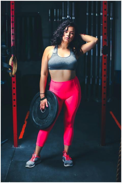 Confident woman in gym attire holding a weight, sh