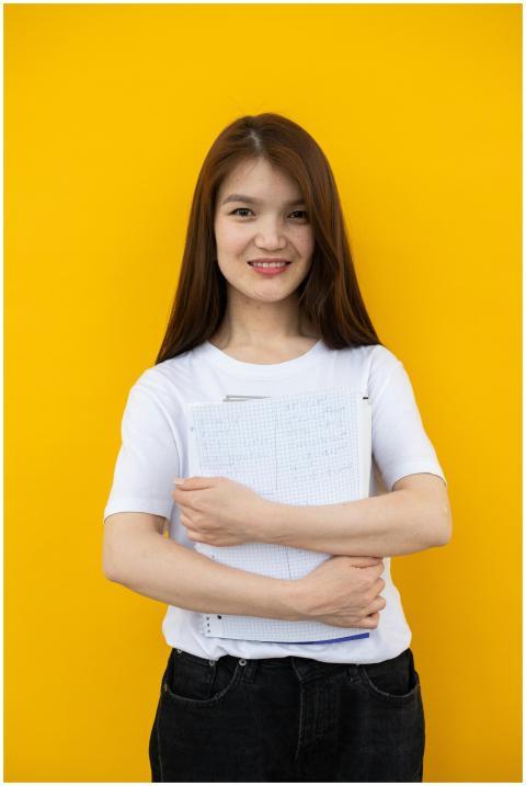 Cheerful young woman student stands with notebook