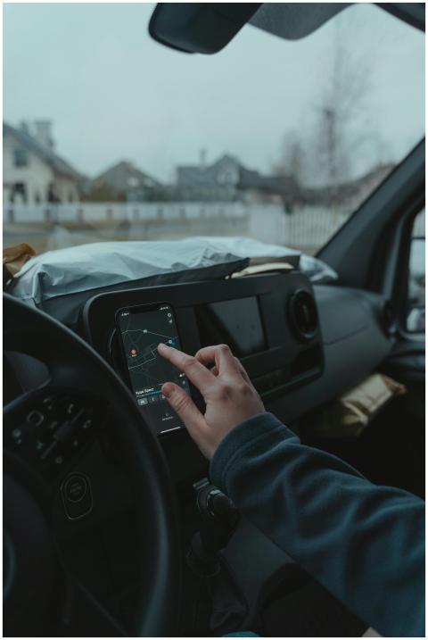 Hand using smartphone GPS inside car on a cloudy d