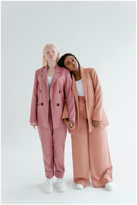 Two women in fashionable suits pose elegantly agai