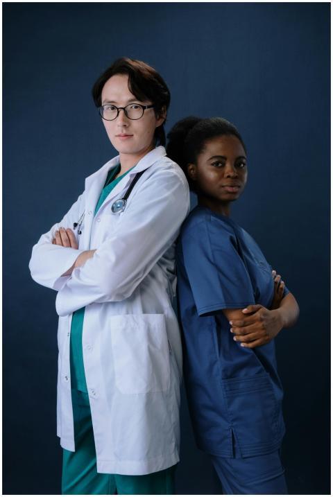Two diverse medical professionals standing back to