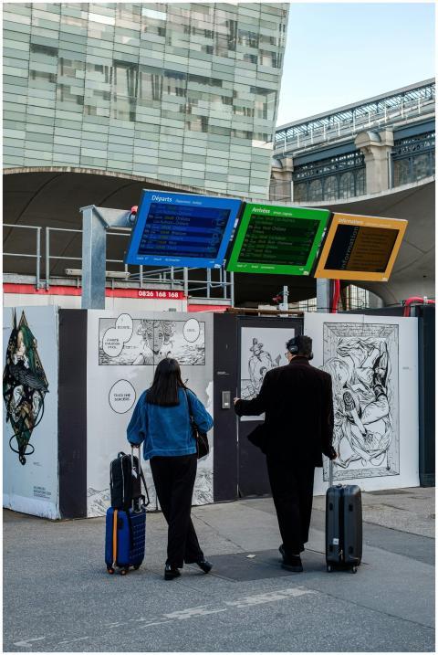 Two travelers with luggage at a modern train stati