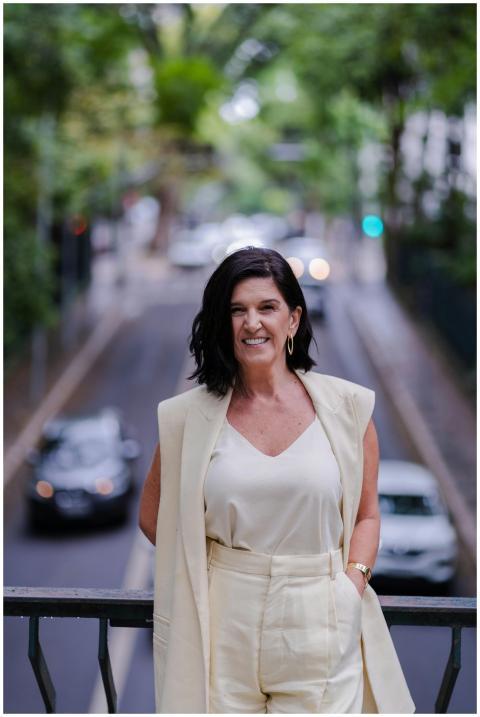 Smiling woman in neutral attire stands on a city b