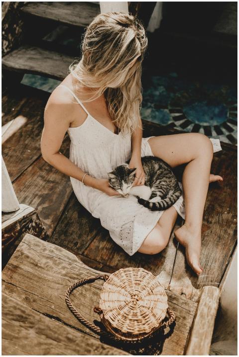 A woman in a white dress sitting indoors petting a