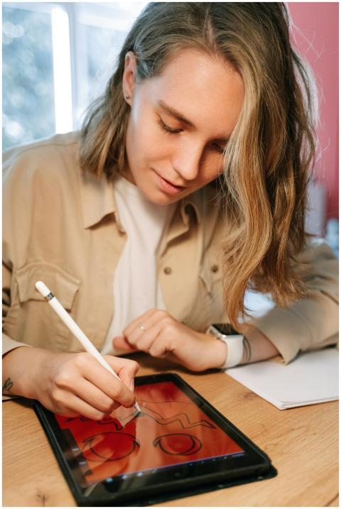 A young woman using a stylus on a tablet to create