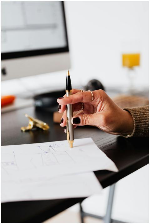 A woman's hand holding a pen, working on paperwork
