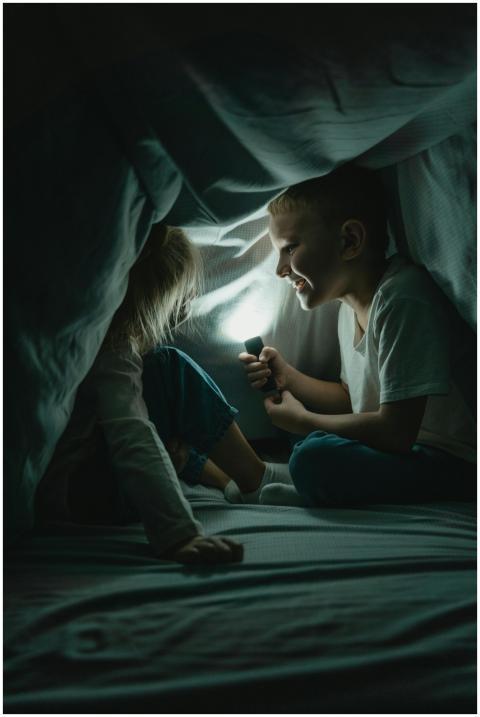 Two children enjoying storytelling with a flashlig
