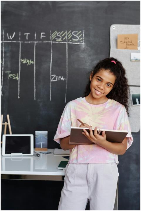 Teen girl smiles while studying indoors, holding a