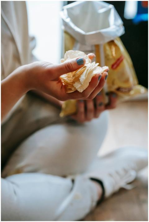 A close-up image of a hand holding potato chips fr