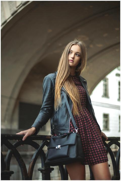Stylish woman poses with a black leather jacket an