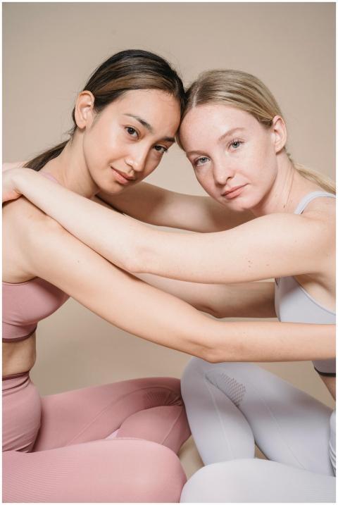 Two women in athletic wear embrace during a studio