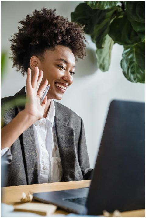 Cheerful businesswoman waving during a remote vide