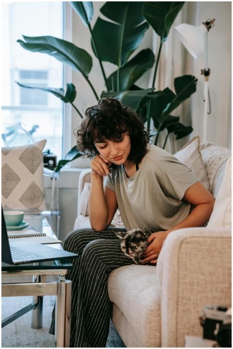 A young woman studying at home with her pet cat on