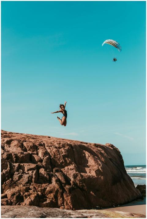 A woman jumps off a rock on a Brazilian beach with