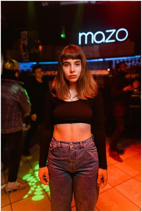 A woman stands in a stylish nightclub with vibrant