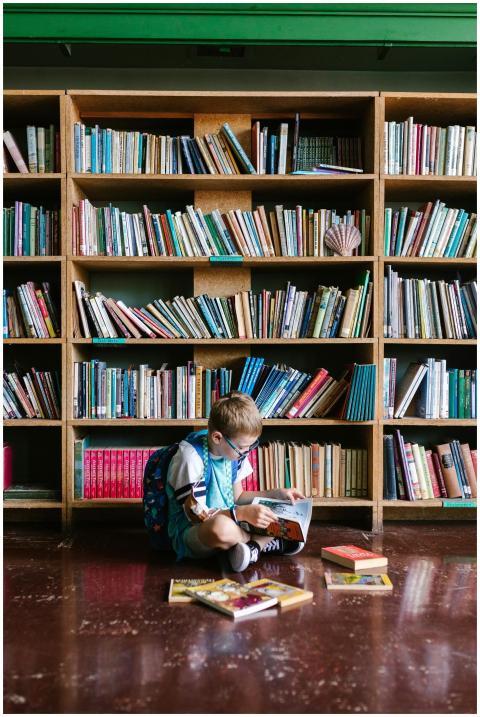 A young boy sitting on the floor reading a book in