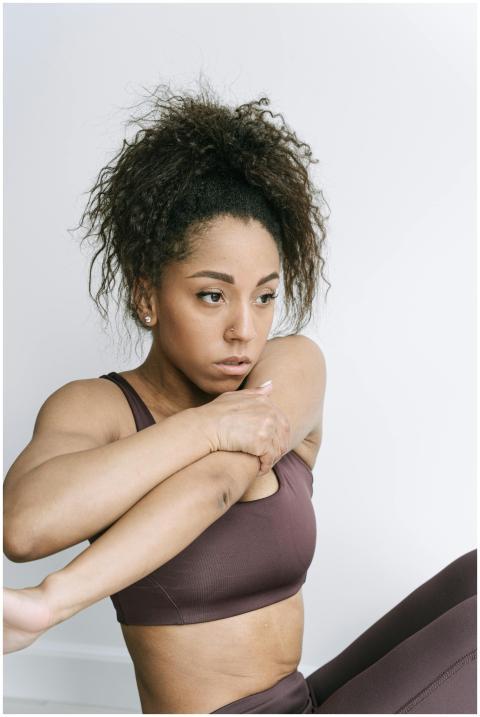 A woman with curly hair stretches in activewear, p