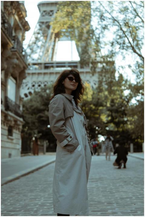 Stylish woman in a trench coat stands near the Eif