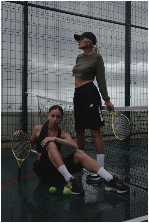 Two women pose confidently on a tennis court, show