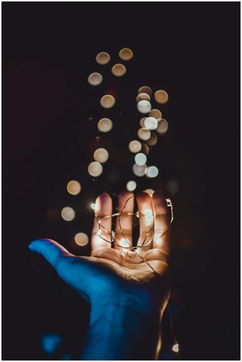A close-up of a hand holding glowing string lights