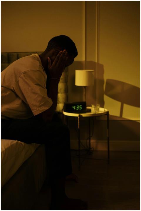 A man sitting on the edge of a bed in a dimly lit
