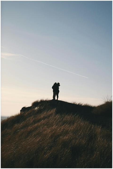 A silhouette of a couple embracing on a hill as th