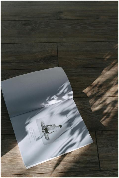 An open book on a wooden floor with artistic shado