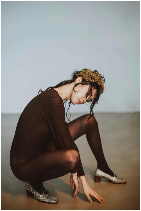 A woman in a chic outfit poses artistically indoor