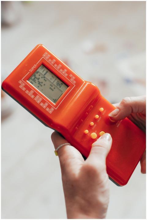 Close-up of hands playing a retro handheld game co