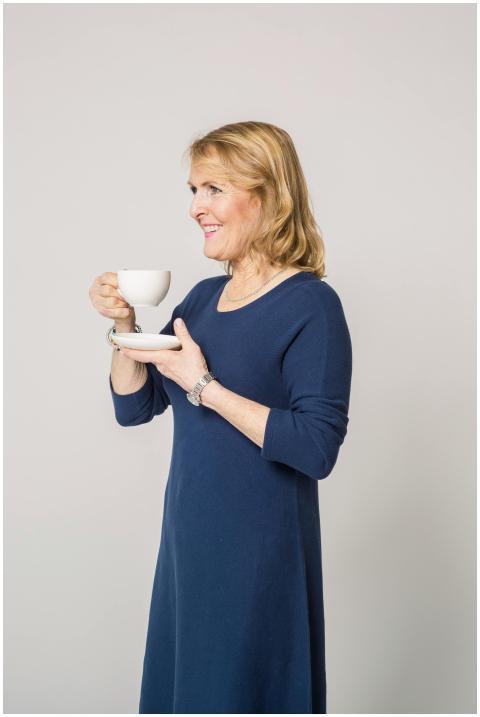 A senior woman in a blue dress smiling while holdi