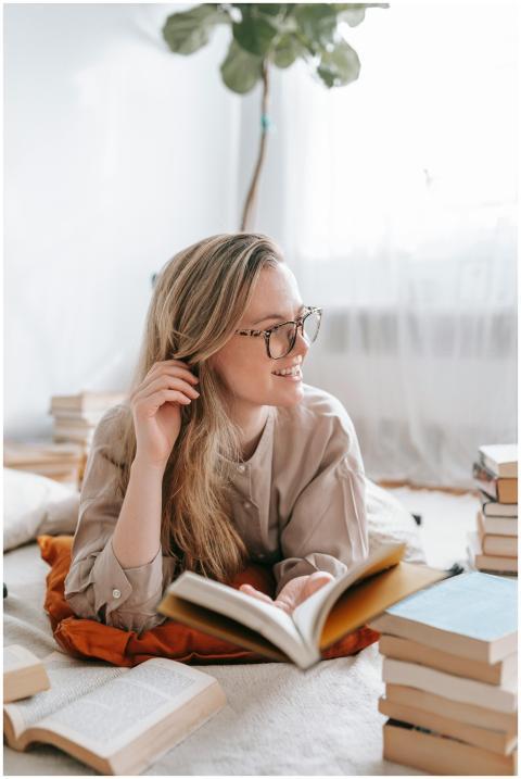 Clever young female lying on cushion and reading n