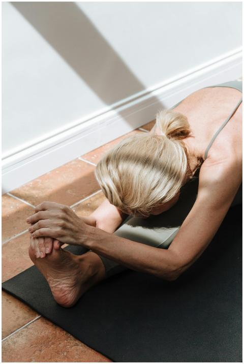 Woman performing a seated forward bend on a yoga m