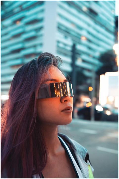 A young woman with futuristic sunglasses poses in
