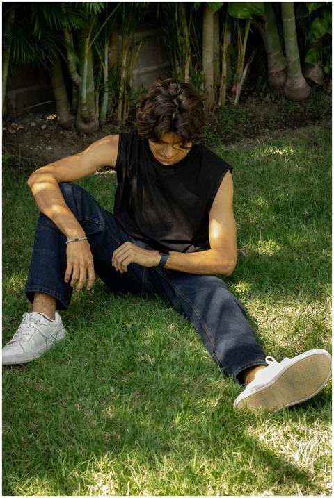 Teenager sitting on grass in casual clothes with a