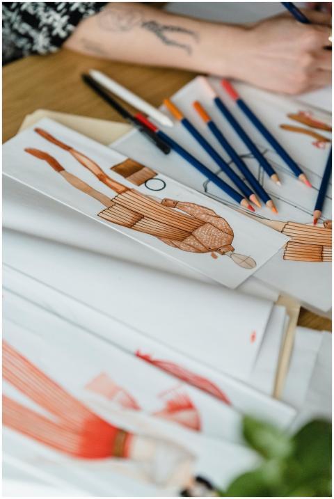 Close-up of fashion design sketches with pencils o
