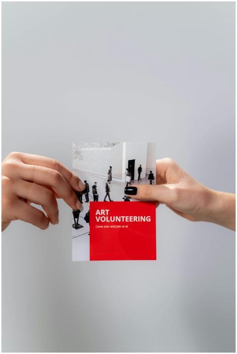 Close-up of hands holding an art volunteering flye