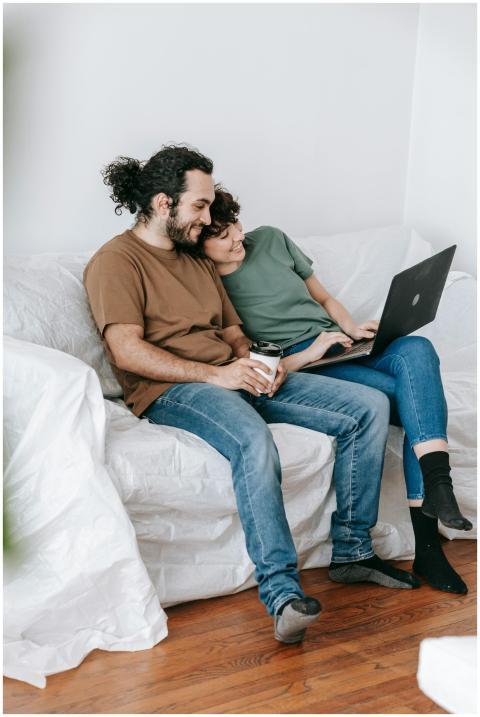 A couple sitting on a sofa, browsing a laptop toge