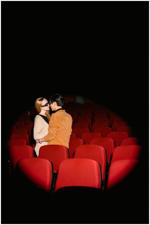 A couple kissing in a movie theater surrounded by