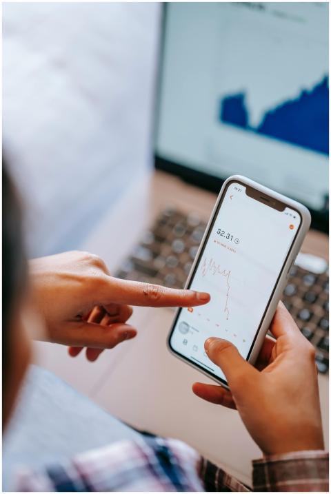 Close-up of hands using smartphone to analyze stoc