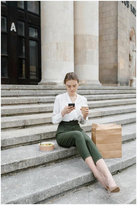 Woman sitting on steps using a smartphone while en