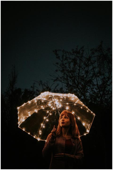 A woman holding a lit umbrella in a dark outdoor s