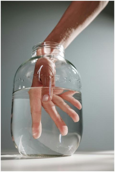 Close-up of a hand submerged in water within a cle