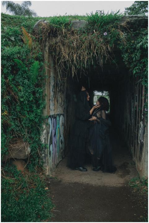 Two people in a dark tunnel with graffiti and gree