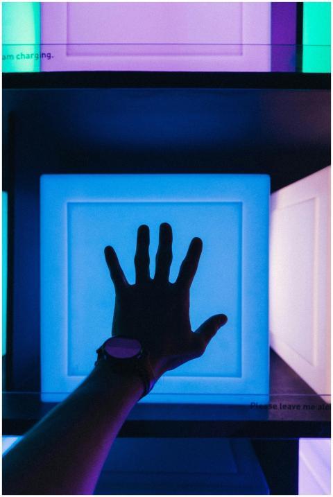 Silhouette of a hand reaching toward a glowing blu